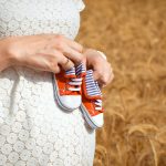 Pregnant woman holding baby sneakers