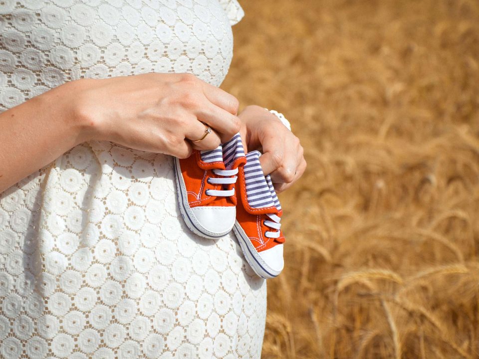 Pregnant woman holding baby sneakers